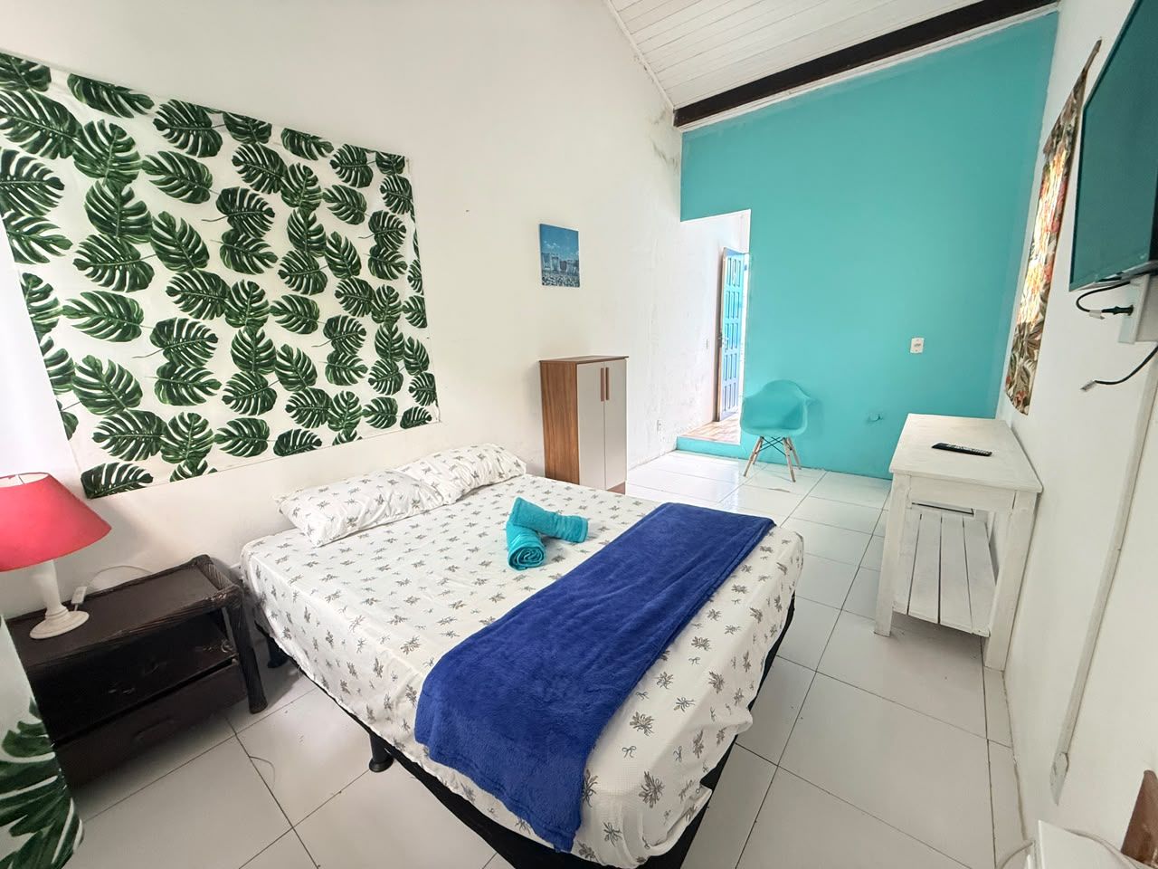 A bedroom with a bed, a nightstand, a desk, and a chair.