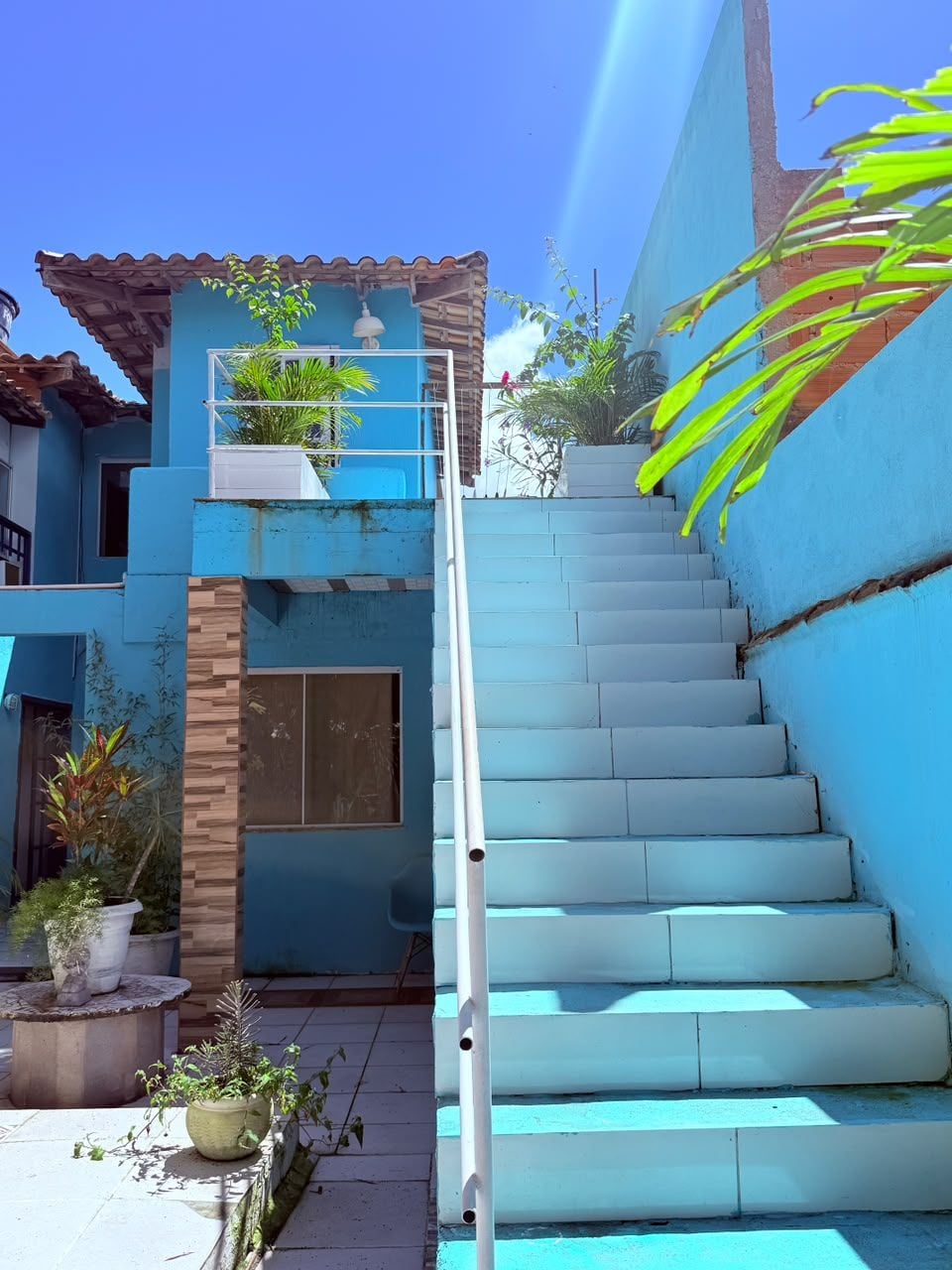 A blue building with a staircase leading to a balcony.