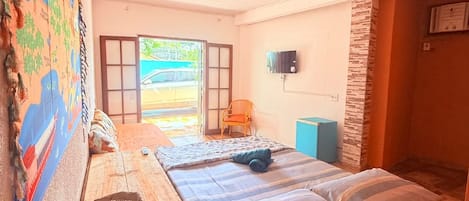 A room with a bed, a TV, a chair, and a large window.