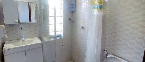 A bathroom with a toilet, a sink, a shower, and a mirror.