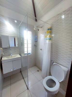 A bathroom with a toilet, a sink, a shower, and a mirror. - Pousada E Apartamento Buda Buzios (Buzios)