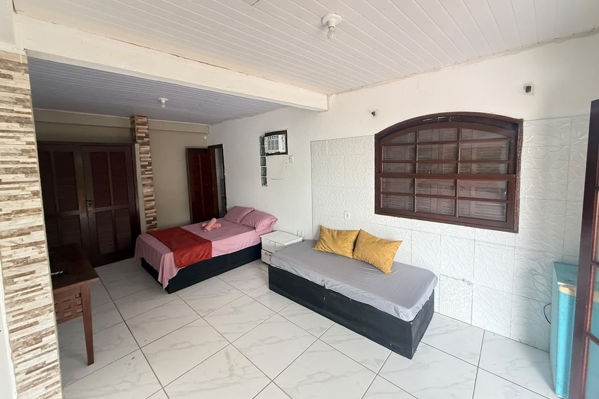 A room with two beds, a small table, and a window with a decorative frame.