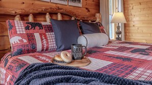 Una camera accogliente con una testiera in legno, una coperta trapuntata, un comodino con una lampada e un piatto con pasticcini.