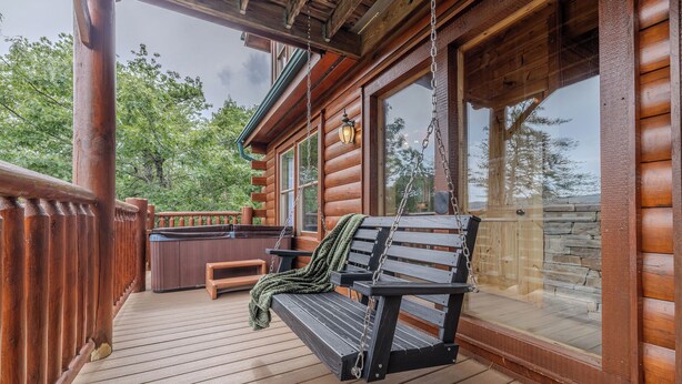 Un patio in legno con una panchina e una vasca idromassaggio.