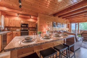 A spacious kitchen with wooden cabinetry, granite countertops, and a central island with seating. - Rocky Top Retreat | Accessible | Mt Views |Hot Tub (Sevierville)