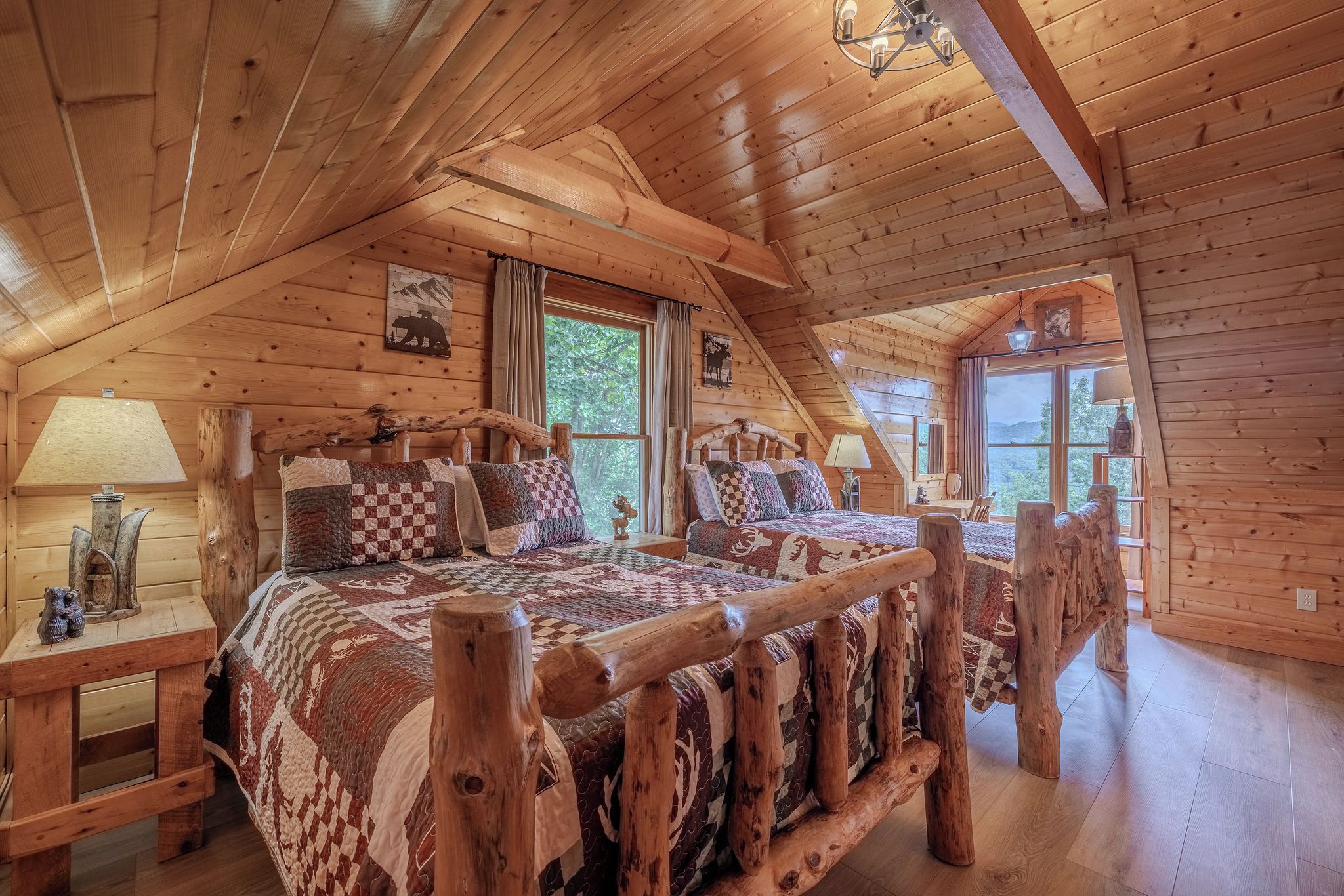 Une chambre dans un chalet en rondins, avec un grand lit, une tête de lit en bois et une vue sur l’extérieur.