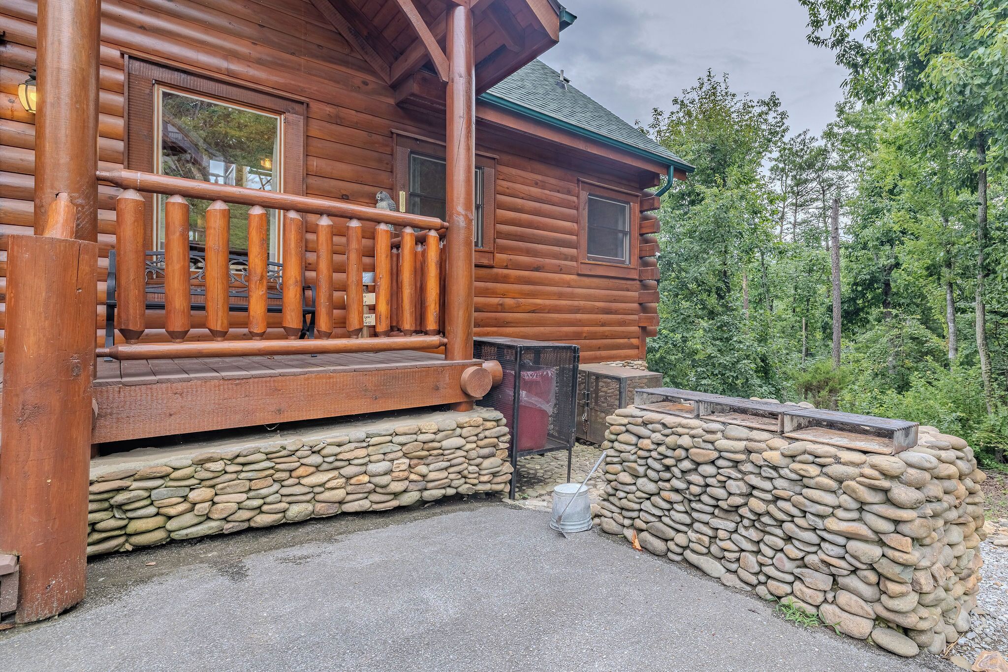 A log cabin with a wooden deck and stone walls.