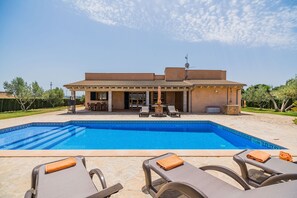 Ein Haus mit Swimmingpool, Sitzgelegenheit im Freien und blauem Himmel.