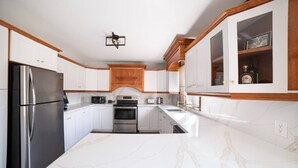 A kitchen with white cabinets, a stainless steel refrigerator, a built-in oven, and a marble countertop. - Rama Ridge with Basketball Court, Hot Tub, Sauna (Orillia)