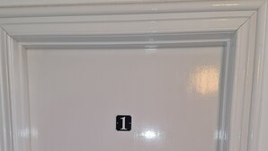 Une porte blanche avec un numéro « 1 » affiché, une serrure et une poignée de porte.