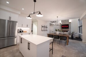 Eine moderne Küche mit Kochinsel, Edelstahlgeräten und einem Essbereich mit Kamin.