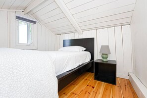 A bedroom with a bed, a nightstand, a lamp, and a window. - Beachfront Cottage #2- Maijac Resort & Marina (Burk`s Falls)