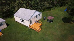 A single-story house with a deck, a barbecue grill, and a patio umbrella. - Beachfront Cottage #2- Maijac Resort & Marina (Burk`s Falls)