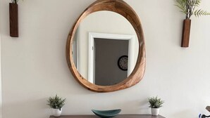 A wooden console table with a mirror above it, flanked by two potted plants. - Modern Orillia Retreat - W/ Game Room (Severn)