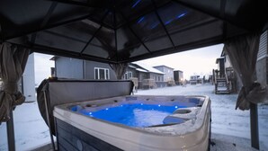 Ein Außen-Hot-Tub mit überdachtem Bereich, umgeben von Häusern in verschneiter Landschaft.