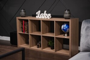 Uma estante de madeira com a palavra 'Lake' na parte superior, contendo livros, um globo e objetos decorativos.