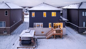 Ein modernes, zweistöckiges Haus mit überdachter Terrasse und Whirlpool.
