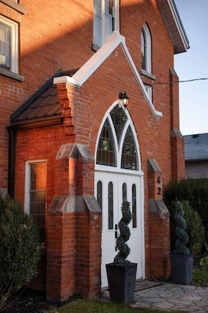 A brick building with a white door, a small porch, and a number '42' on the wall.