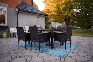 An outdoor patio with a table and chairs, a grill, and a house in the background. - The Chapel Retreat with Hot Tub and Game Room (Bluevale)