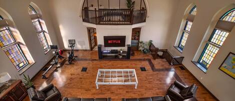 A spacious living room with a large TV, leather sofas, a coffee table, and a balcony with a railing.
