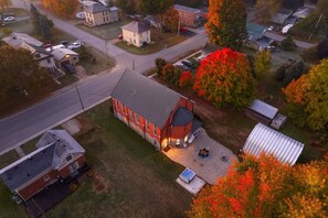 An aerial view of a residential area with a prominent red building featuring a large garage and a patio area with outdoor seating.