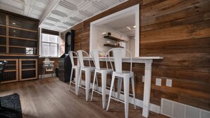 Ein Essbereich mit weißen Stühlen, einer Holzwand und einer Decke mit weißen Paneelen.
