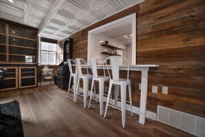 A dining area with white chairs, a wooden wall, and a ceiling with white paneling. - The Chapel Retreat with Hot Tub and Game Room (Bluevale)