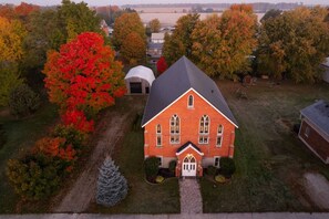 A red brick house with a gabled roof, a front porch, and a small front yard with a tree and a snowman. - The Chapel Retreat with Hot Tub and Game Room (Bluevale)
