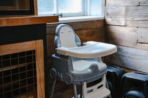 Una silla alta en una habitación con paredes de madera y un ventanal.