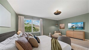 A hotel room with a large bed, a desk, a chair, a dresser, and a window with curtains. - New Listing! Casa Solara - Private Pool, Spa, Super Close to Disney World! (Kissimmee)