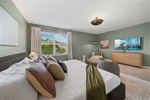 A hotel room with a large bed, a desk, a chair, a dresser, and a window with curtains. - New Listing! Casa Solara - Private Pool, Spa, Super Close to Disney World! (Kissimmee)