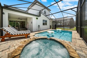 A swimming pool with a hot tub, lounge chairs, and a covered patio area. - New Listing! Casa Solara - Private Pool, Spa, Super Close to Disney World! (Kissimmee)