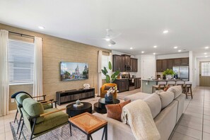 Una sala de estar moderna con un sofá, sillones, una mesa de centro y un televisor montado en la pared.