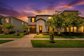 A residential building with a central entrance, a driveway, and a well-maintained lawn. - New Listing! Casa Solara - Private Pool, Spa, Super Close to Disney World! (Kissimmee)