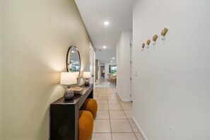 A hallway with a mirror, two lamps, a bench, and a wall with decorative items. - New Listing! Casa Solara - Private Pool, Spa, Super Close to Disney World! (Kissimmee)