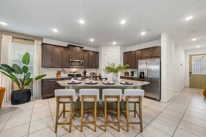 A modern kitchen with a central island, stainless steel appliances, and a potted plant. - New Listing! Casa Solara - Private Pool, Spa, Super Close to Disney World! (Kissimmee)
