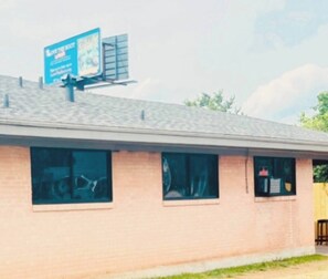 Un bâtiment à la façade en briques, doté de nombreuses fenêtres et surmonté d’un panneau publicitaire.