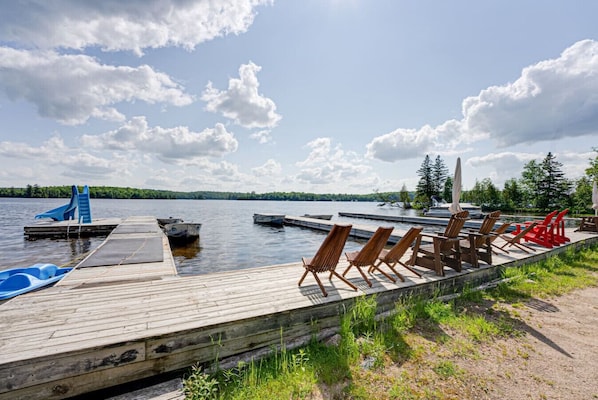 A wooden dock with boats, lounge chairs, and a small pool.
