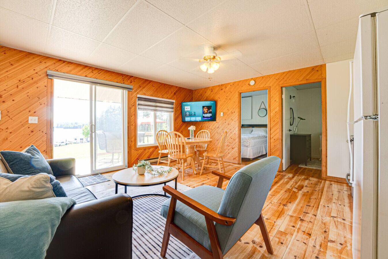 Una habitación acogedora con piso de madera, un sofá, una mesa de comedor con sillas, un televisor y una cama.
