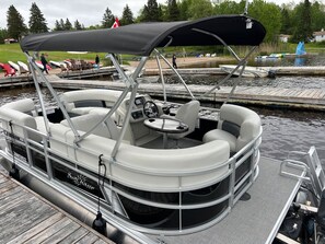 Un bateau ponton était amarré dans une marina, et il était équipé d’un espace de repos abrité, d’un volant et d’une table.