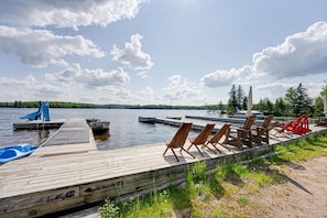 A wooden dock with boats, lounge chairs, and a small pool.