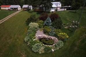 Ein gepflegter Garten mit einem zentralen Teich, umgeben von verschiedenen Sträuchern und Blumen.
