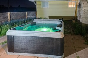 Ein Whirlpool in einer Gartenanlage, im Hintergrund ein Haus.
