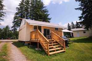 A small wooden cabin with a porch and a staircase.