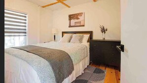 A bedroom with a bed, bedside tables, a dresser, a window with blinds, and a wall-mounted picture. - Beachfront Cabin #5- Maijac Resort & Marina (Burk`s Falls)