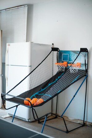 Ein Basketballkorb mit Netz, ein Kühlschrank und eine blaue Wand.