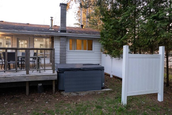 A house with a deck, a hot tub, and a white fence.