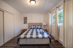 A bedroom with a bed, nightstands, a lamp, and a window with curtains.