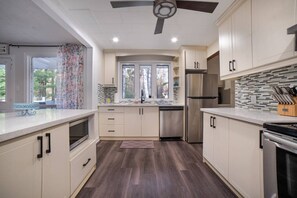 A modern kitchen with a central island, built-in appliances, and a ceiling fan.