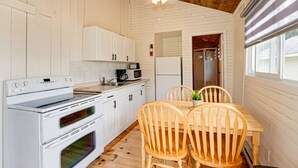A compact kitchen with white cabinetry, a stove, microwave, and a ceiling fan. - Lake Cecebe Retreat #6- Maijac Resort & Marina (Burk`s Falls)